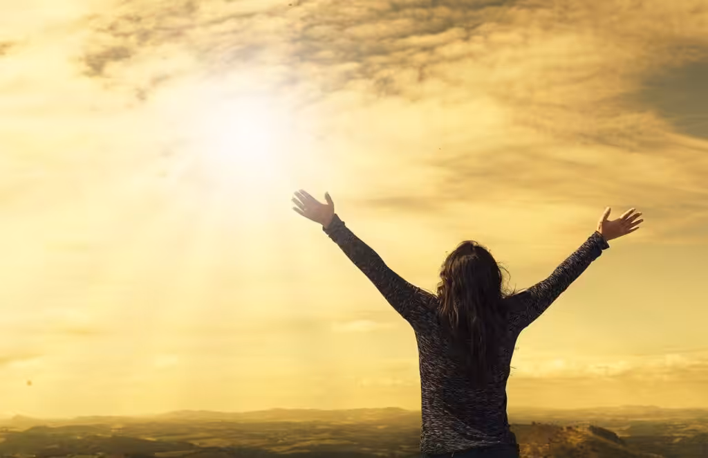 Frau breitet Arme in der Sonne aus